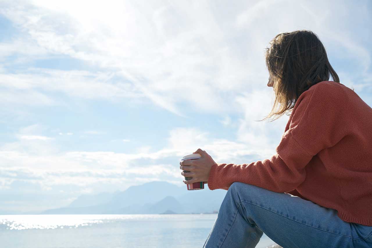 woman sitting outside with a coffee thinking about going to rehab